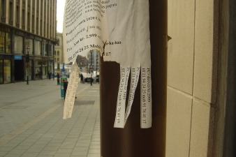 Wall of accumulated stickers and flyposters at a busy urban location